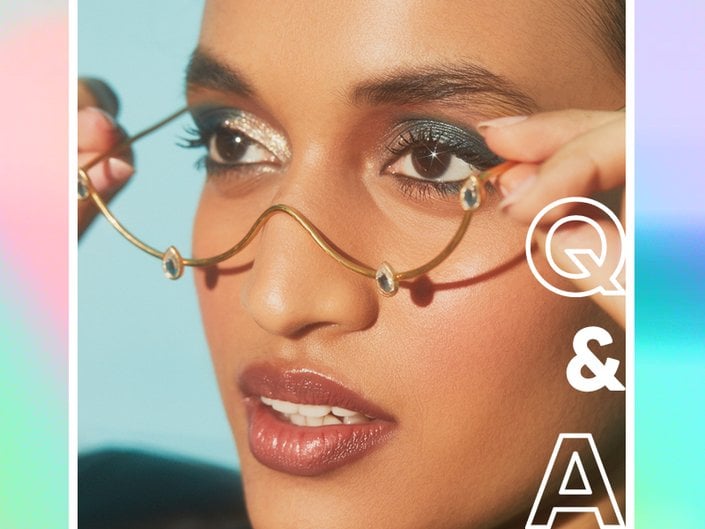 person wearing gold glitter and blue eyeshadow and no lens half frame glasses