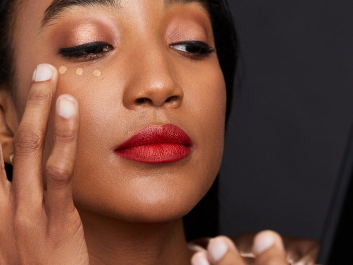 person applying concealer under eye with finger
