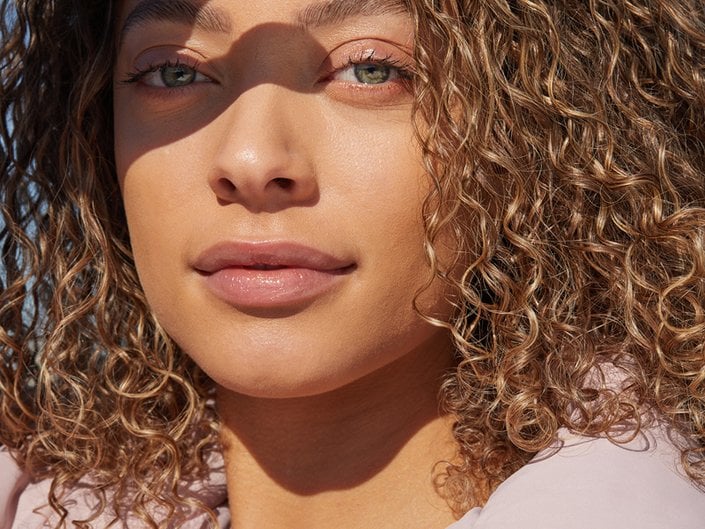 person with green eyes and naturally curly hair wearing natural makeup