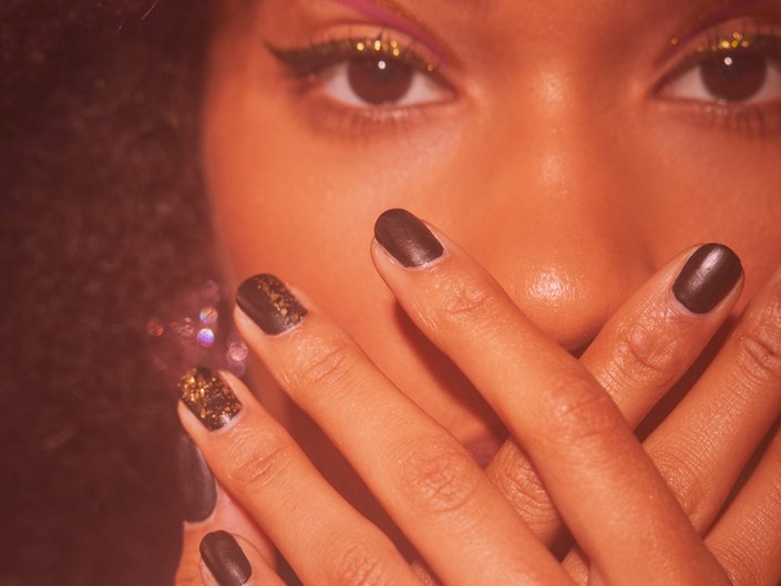 person posing with hands over mouth with nails painted black