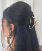 Back of a person’s head with dark hair pulled back with a gold claw clip in a half-up, half-down style