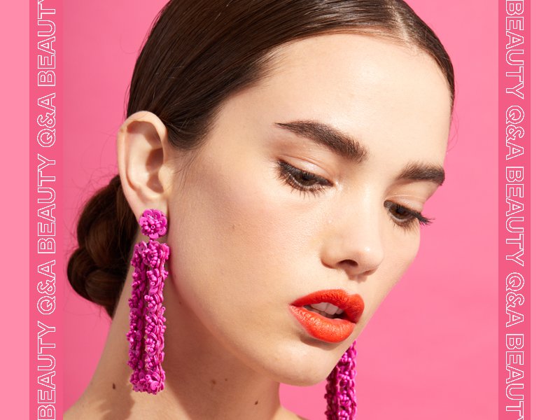 person wearing orange lipstick and magenta drop earrings