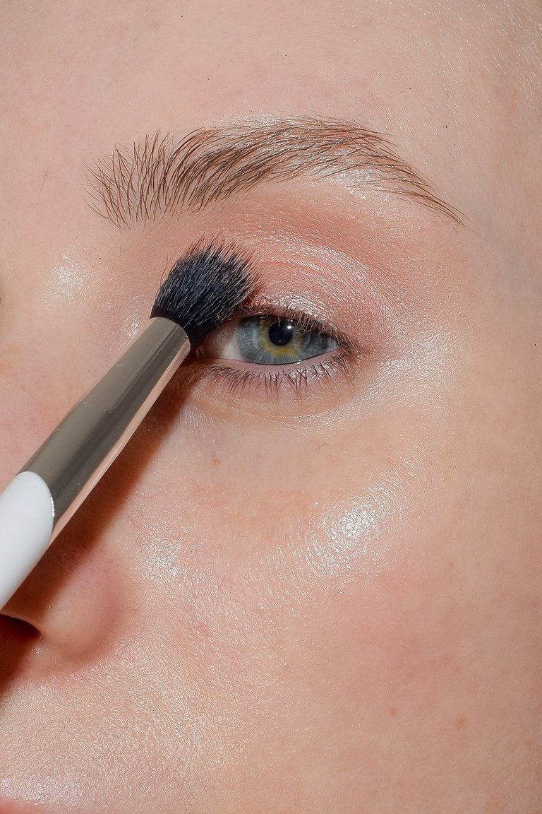 makeup brush applying rose-colored eyeshadow to eyelid
