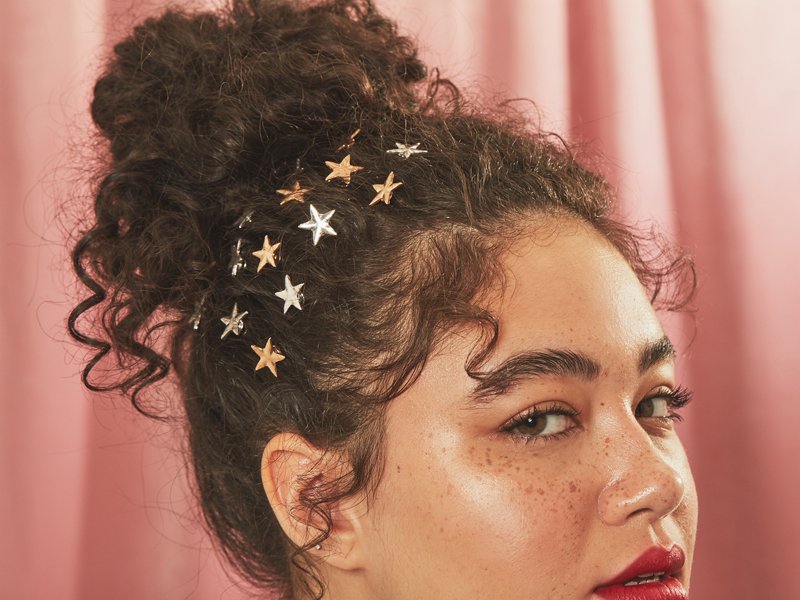 person wearing naturally curly hair in high bun with star hair accessories