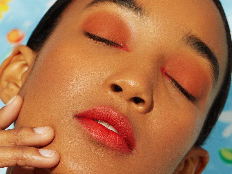 person wearing orange eyeshadow and coral lipstick