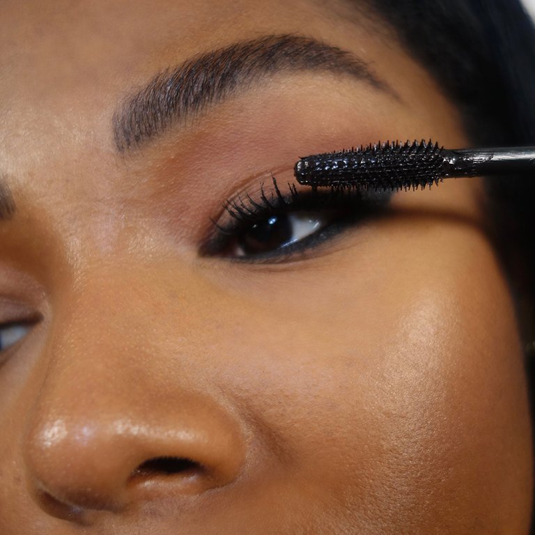 close up of mascara wand applying mascara to lashes
