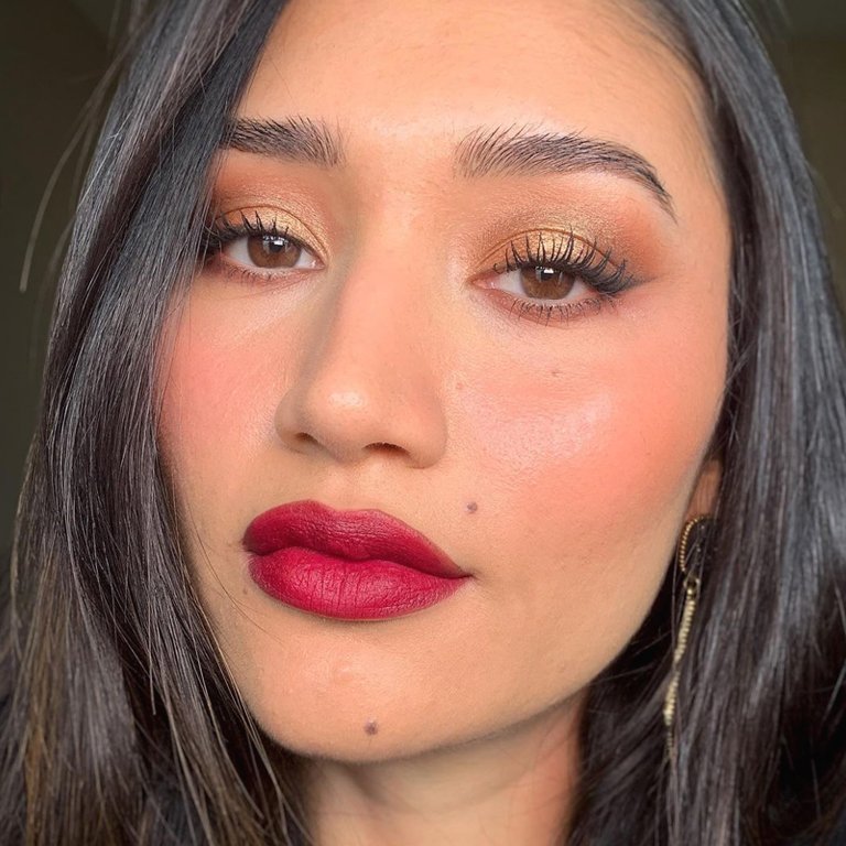 person wearing gold shimmering smokey eye and red lipstick