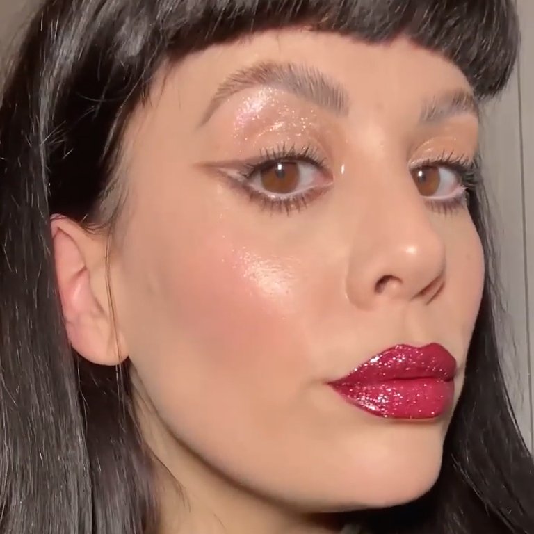 person wearing glitter eyeshadow and red glitter lipstick