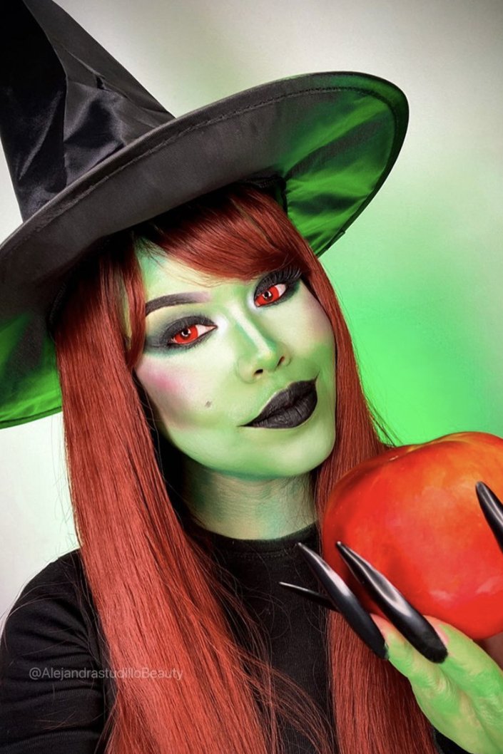 person wearing witch costume, red eye contacts and green face makeup
