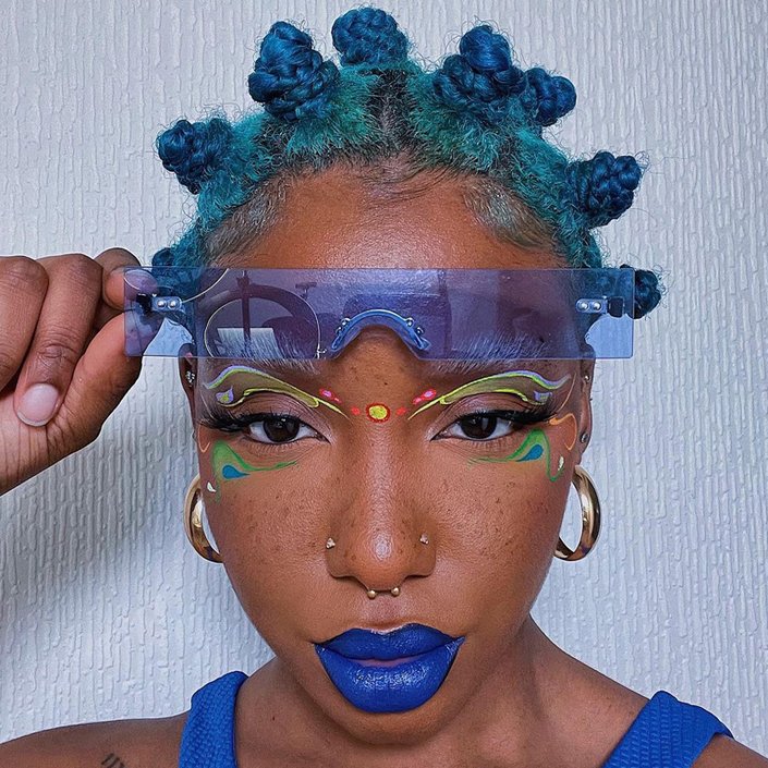 person with blue hair wearing graphic eye makeup and blue lipstick