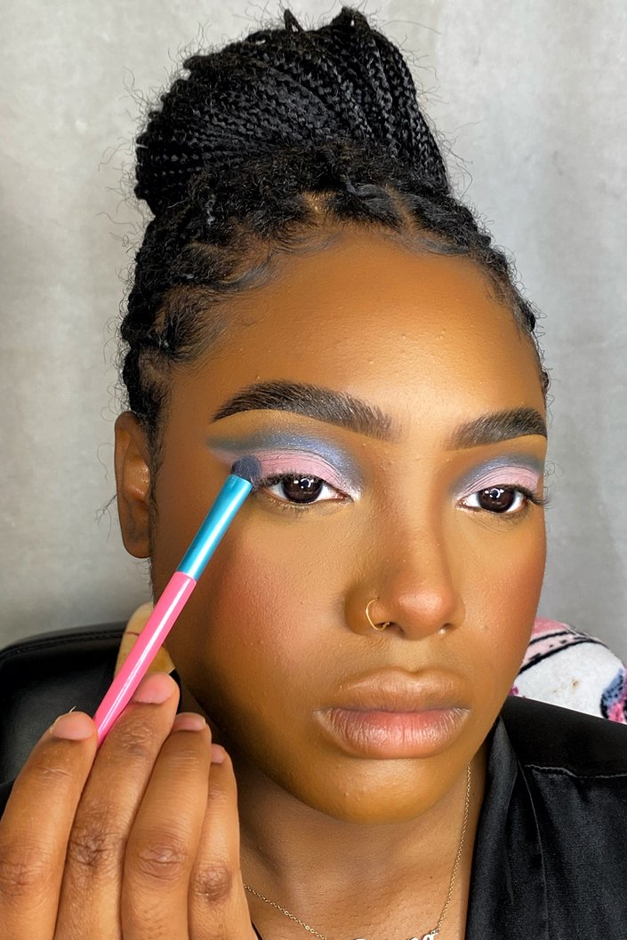 person applying pink eyeshadow to eyelid