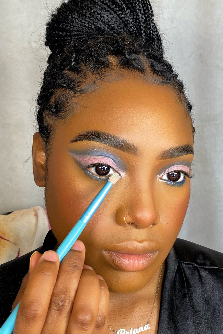 person applying pink eyeshadow to inner corner of eye