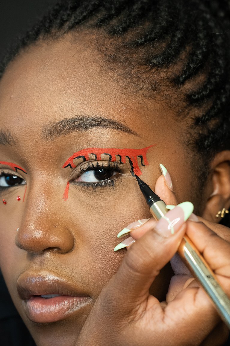 person applying black liquid eyeliner to eyelid