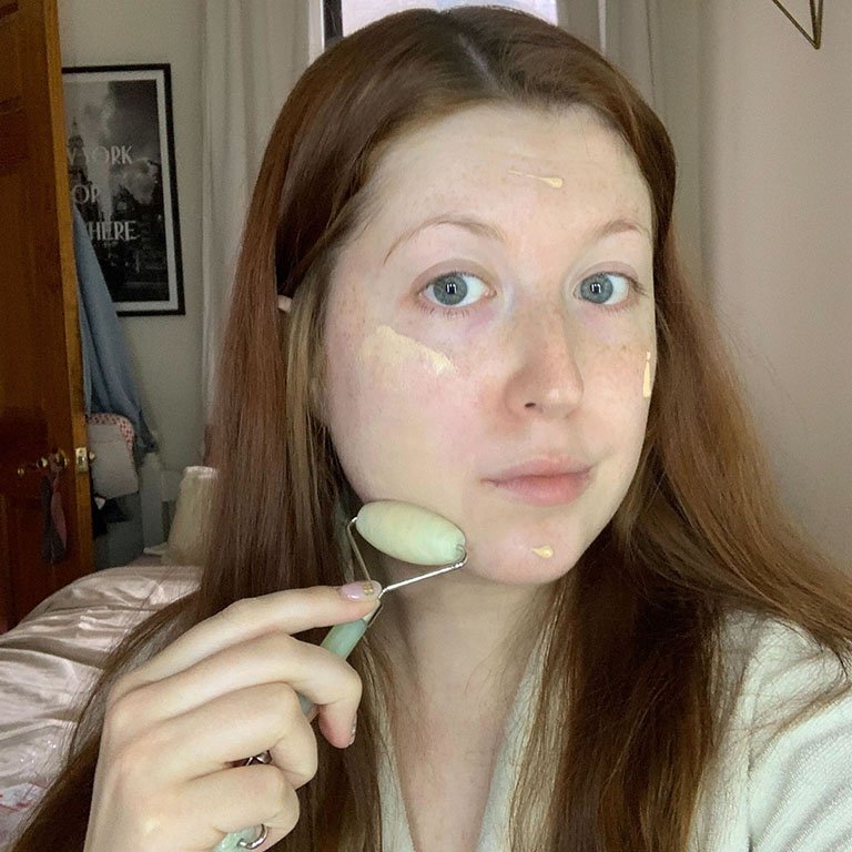 person applying foundation to face with jade roller