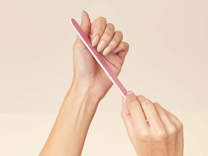 Person filing nails with a pink nail file