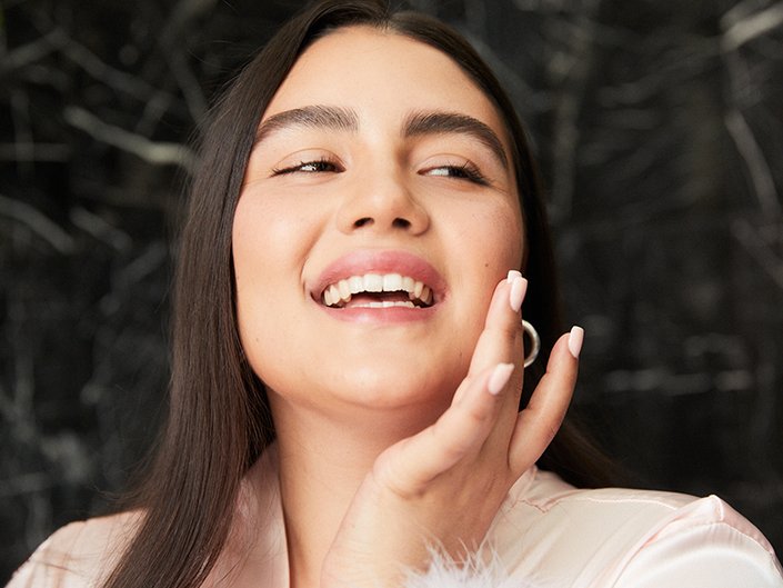 person smiling and posing with finger on cheek