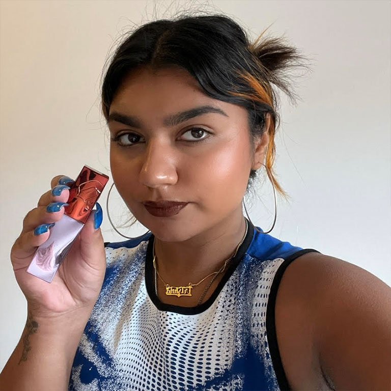 Trishna wears and holds up the Urban Decay Vice Lip Bond Glossy Liquid Lipstick in Once Strangers