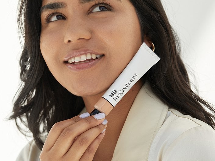 Person smiling and holding the YSL Beauty Nu Bare Look Tint