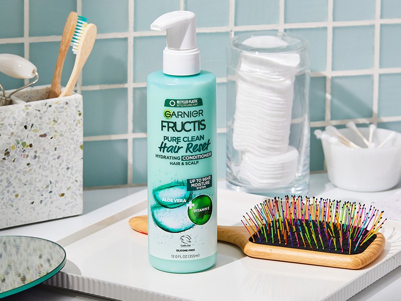 Garnier Fructis Pure Clean Hair Reset Clarifying Shampoo next to toiletries and hairbrush