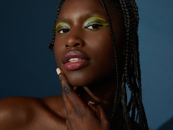 Photo of person with green eyeshadow and pouty lips on a dark blue background.