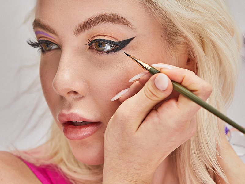 photo of person applying a bat wing eye look with black eyeliner