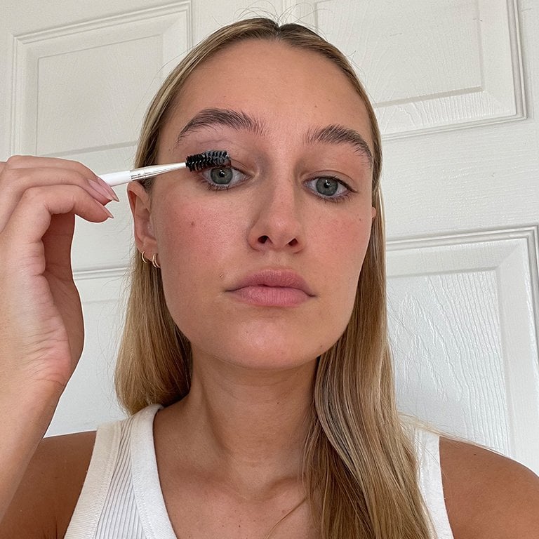 Selfie of editor applying petroleum jelly to her eyelashes with a spoolie brush