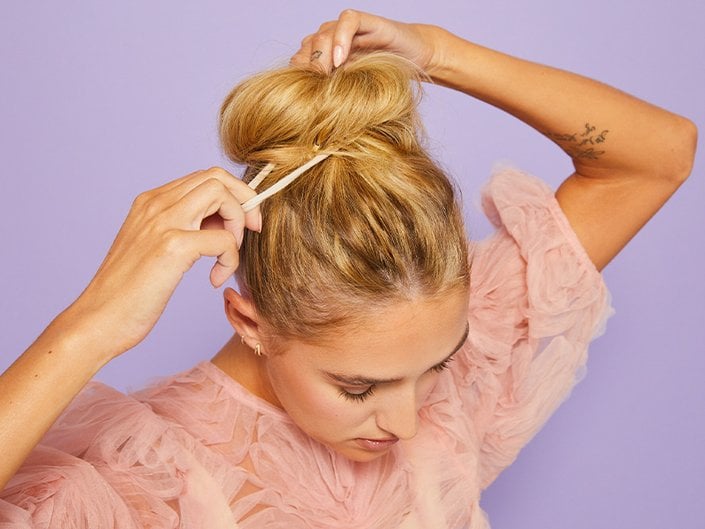 photo of person creating a messy bun on purple background