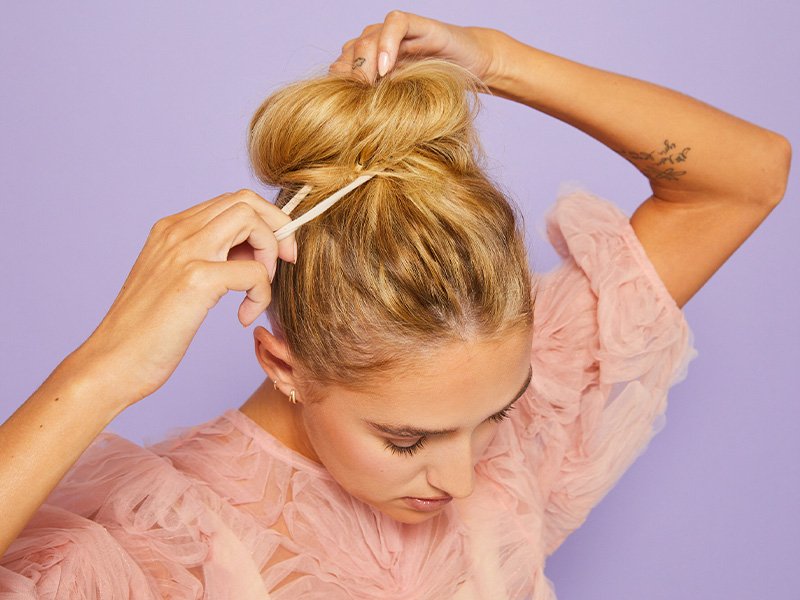 photo of person creating a messy bun on purple background