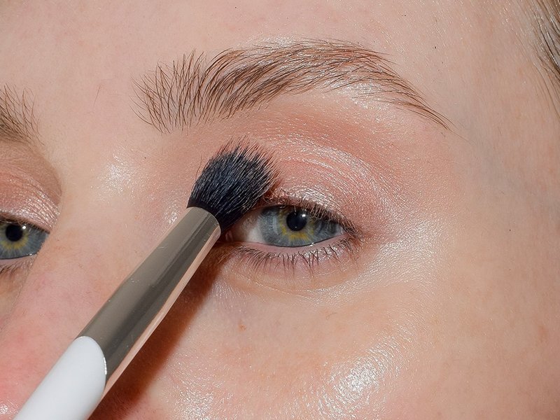 Close-up photo of a model blending a transition shade in her crease