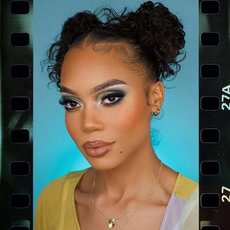 person wearing green smokey eye makeup with hair in two buns