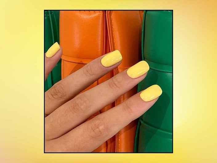 Close-up of a person’s hand painted with yellow nail polish collaged on a yellow background