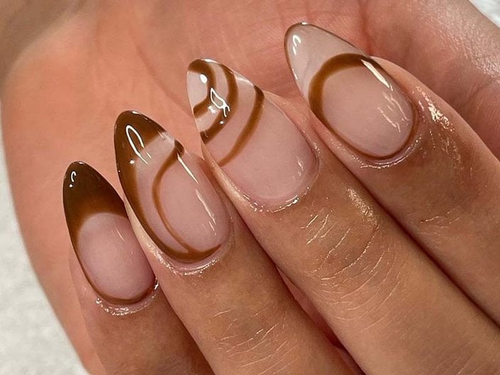 Close-up image of a hand with long brown and nude manicured Gel-x nails