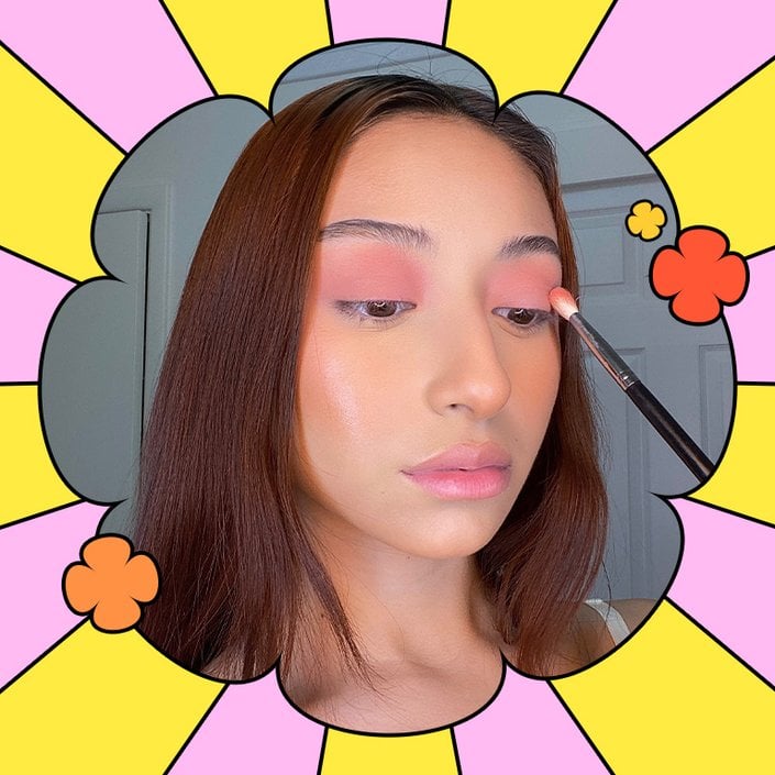 person applying peach eyeshadow to eyelid with makeup brush
