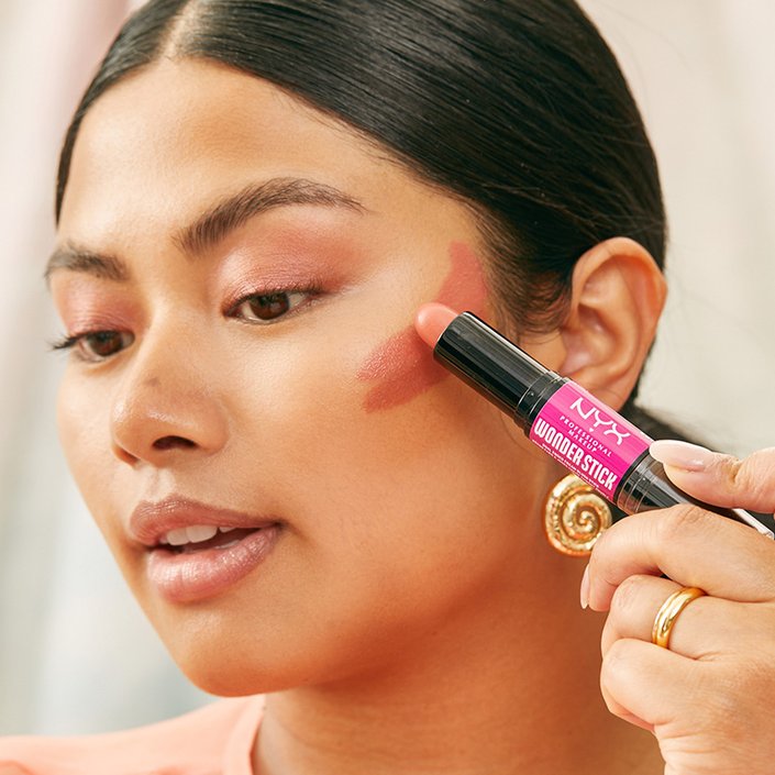 person applying cream blush on upper cheeks