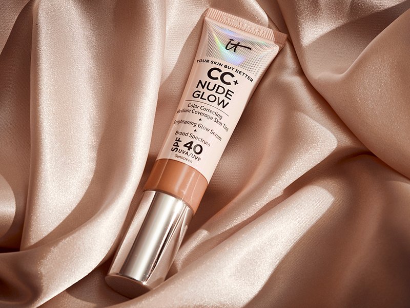 IT Cosmetics CC+ Nude Glow Lightweight Foundation + Glow Serum with SPF 40 on a tan fabric background.