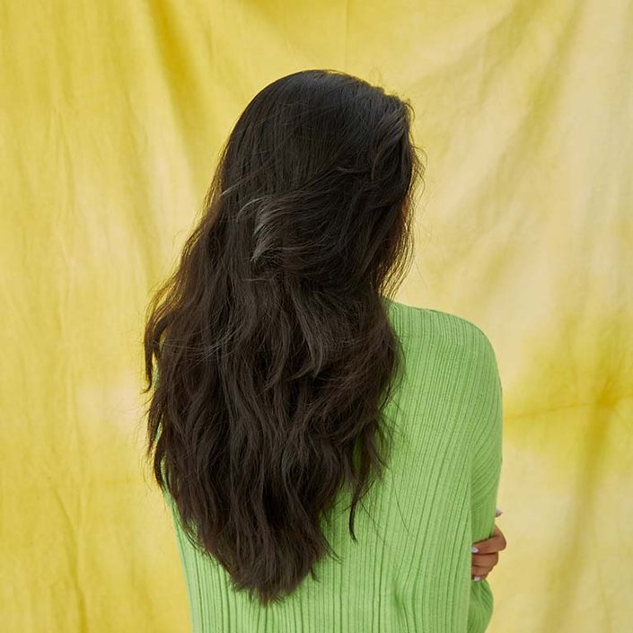 person with long dark brown hair turned away from camera