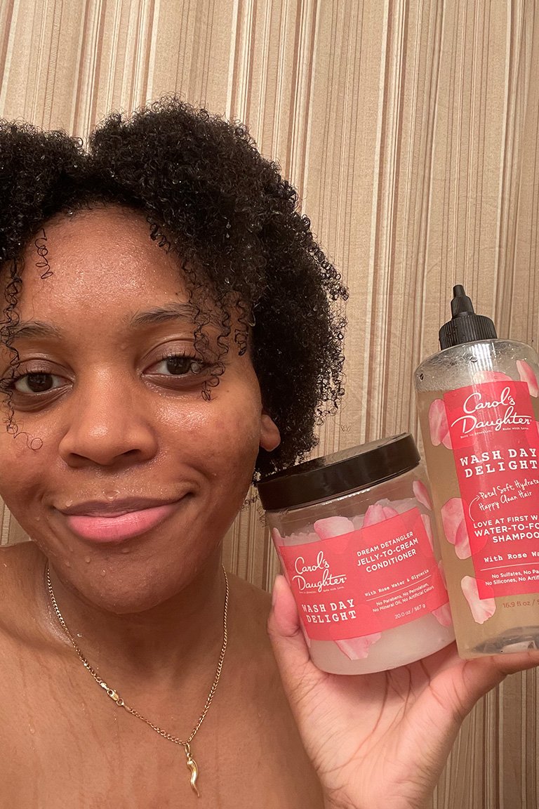 person with wet curly hair holding Carol's Daughter Wash Day Delight Jelly to Cream Conditioner and Carol's Daughter Wash Day Delight Sulfate-Free Shampoo