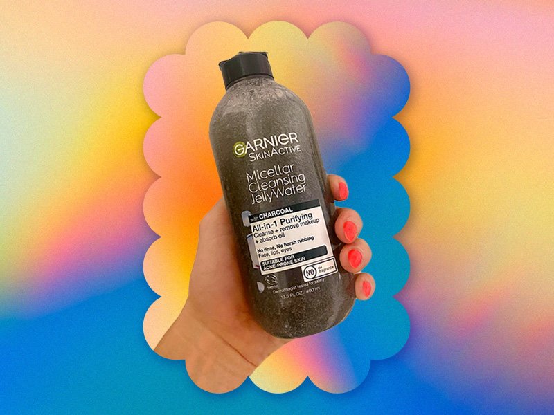 photo of hand holding Garnier Charcoal Micellar Jelly Water on rainbow background