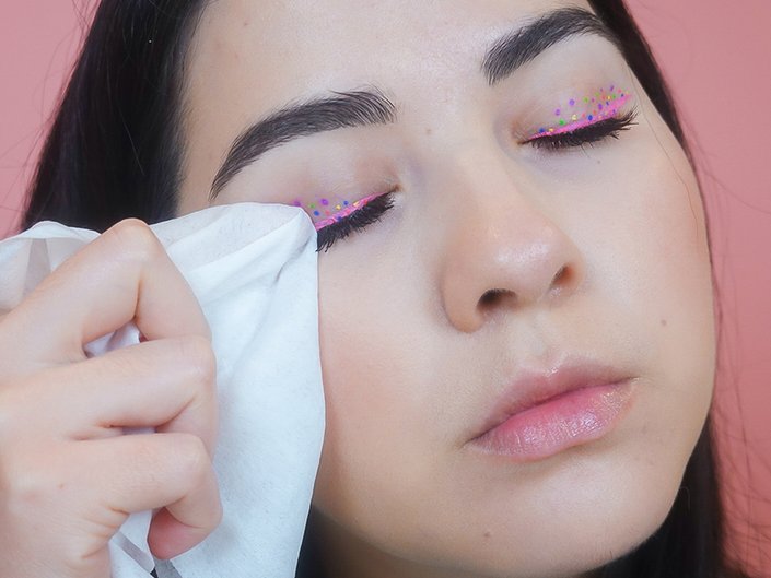 Person removing sparkly pink eyeliner with a tissue