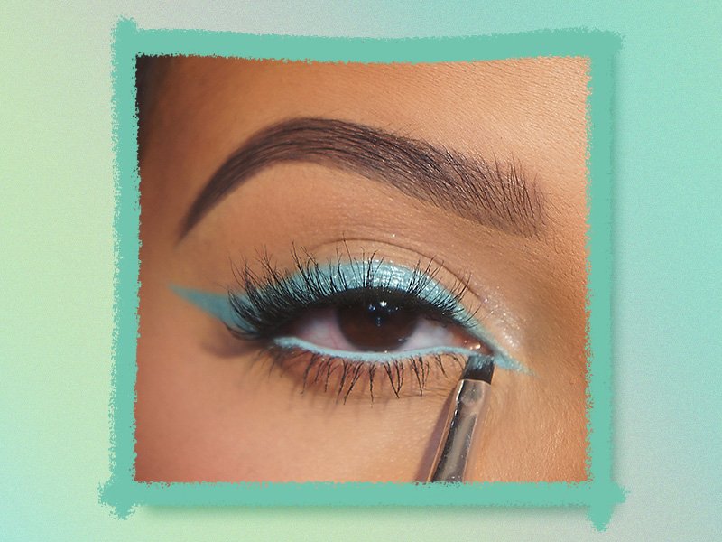Person applying blue eyeliner to the inner corner of their eye