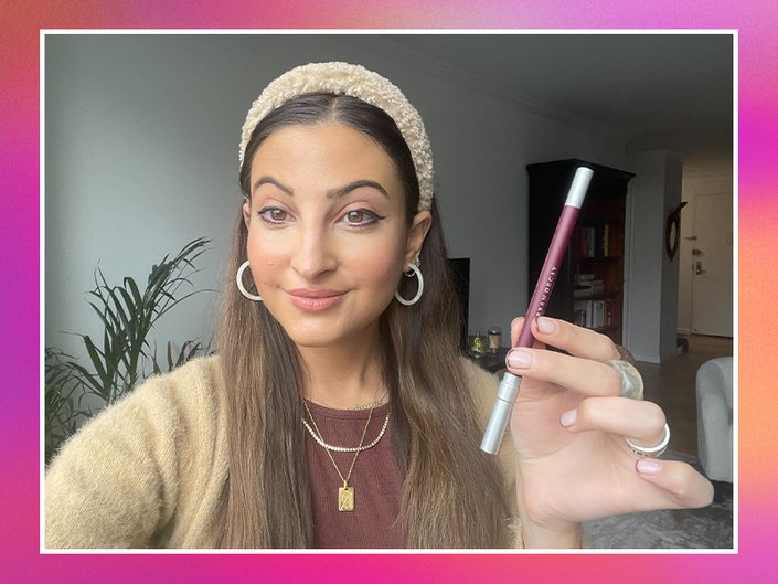 Image of a woman holding the Urban Decay 24/7 Glide-On Waterproof Eye Pencil in Alkaline on a hot pink background