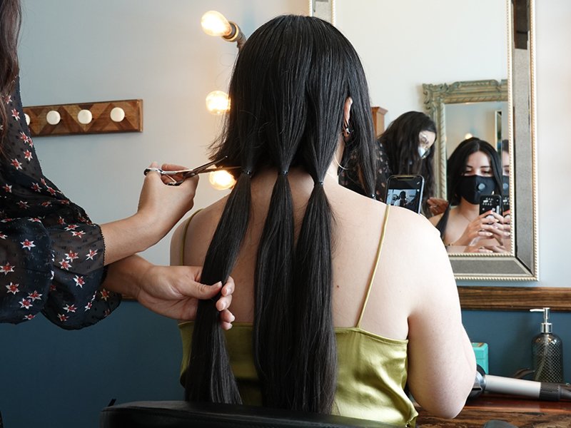 Image of woman with long black hair getting her hair cut