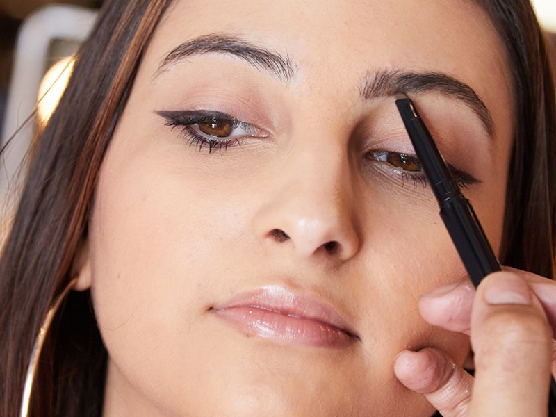 person applying brow makeup using a pencil