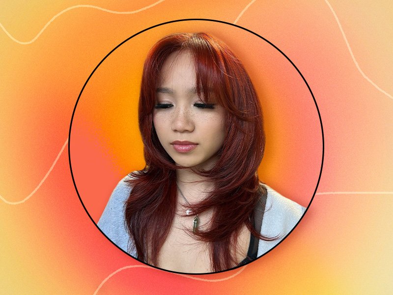 Picture of a person with red layered hair on an orange gradient background 