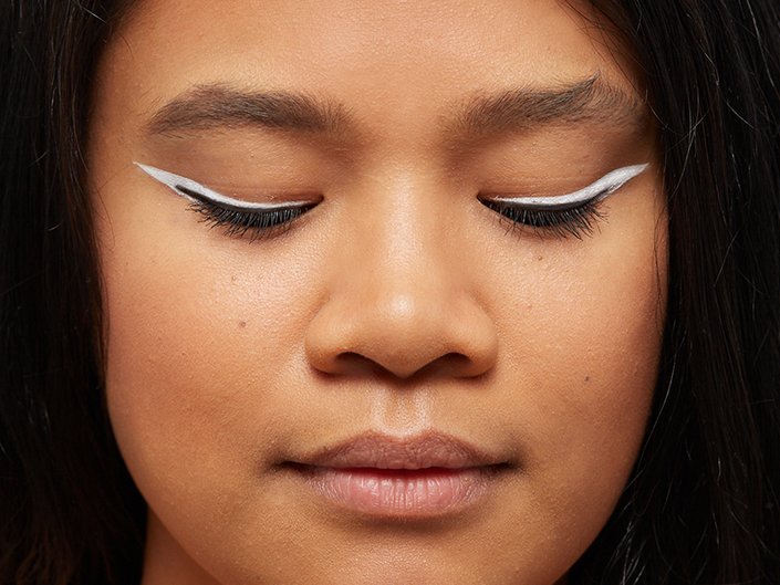 Picture of model with their eyes closed, wearing white eyeliner