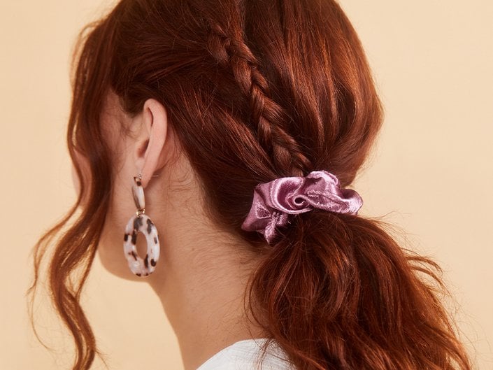 Picture of a model with red hair in a ponytail with a pink scrunchie