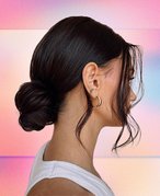 Picture of a person in profile with dark hair in a bun, on a multicolored graphic background 