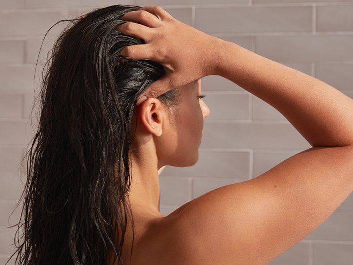 Picture of a model with their back turned to the camera, washing their hair