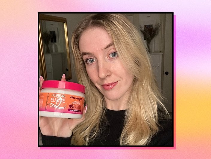 Picture of a person holding the L'Oréal Paris Elvive Dream Lengths Savior Fiber Mask against a graphic purple and orange gradient background