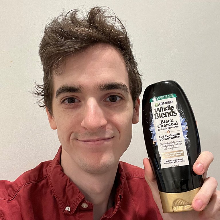 stephen holding the Garnier Whole Blends Black Charcoal and Nigella Flower Oil 